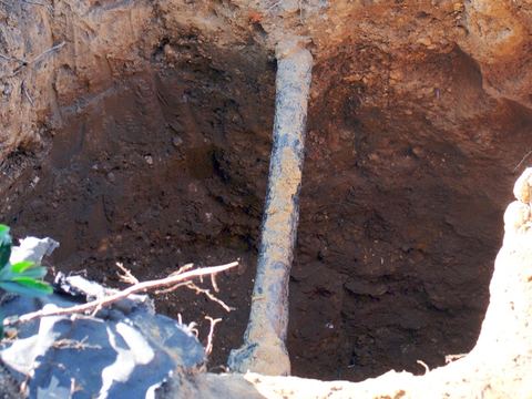 A gray lead water pipe exposed at the bottom of an excavated hole in Washington, D.C.
